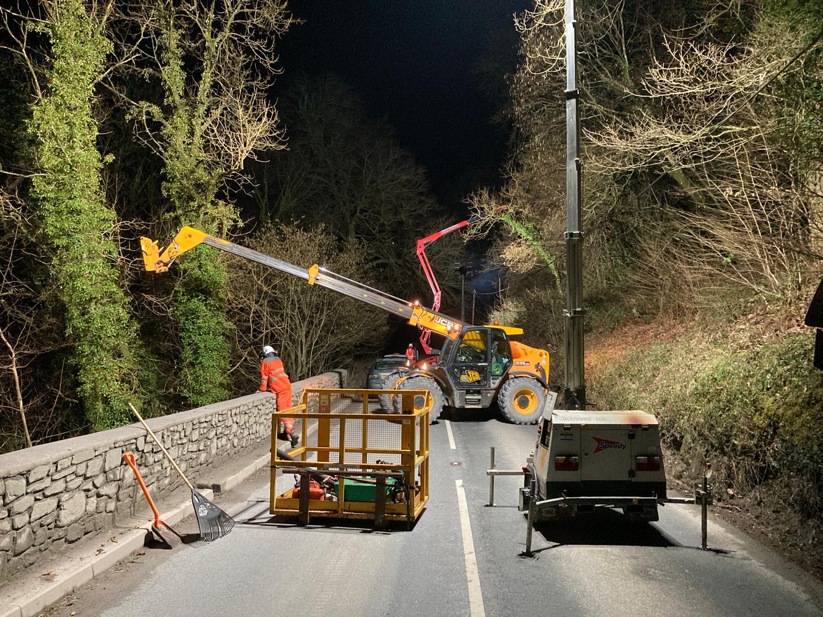 Treebor team carrying out night time tree work with a telehandler and access platform on a rural road in Somerset